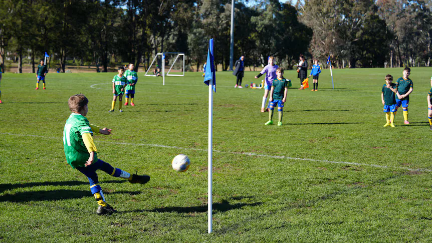 Football and boots beside the touchline of a grass pitch