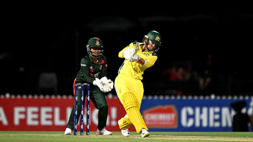 Cricket bat and ball beside the stumps on a pitch